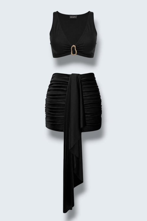 The Saint 54 black two-piece mini set featuring a fitted crop top with gold accent and a draped gathered mini skirt.