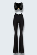 The Saint 54 black two-piece set featuring a cropped top with a gold accent and high-waisted flared wide-leg pants.