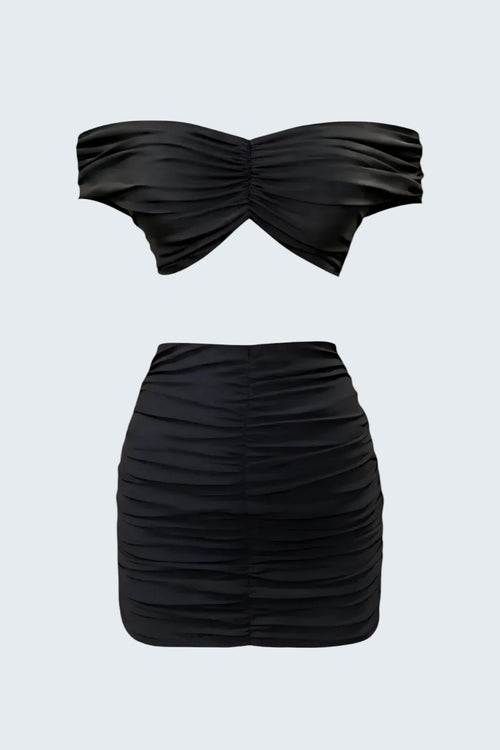 The Saint 54 black ruched strapless top and bodycon mini skirt set. Off-shoulder top with draped detail. Skirt has adjustable length.