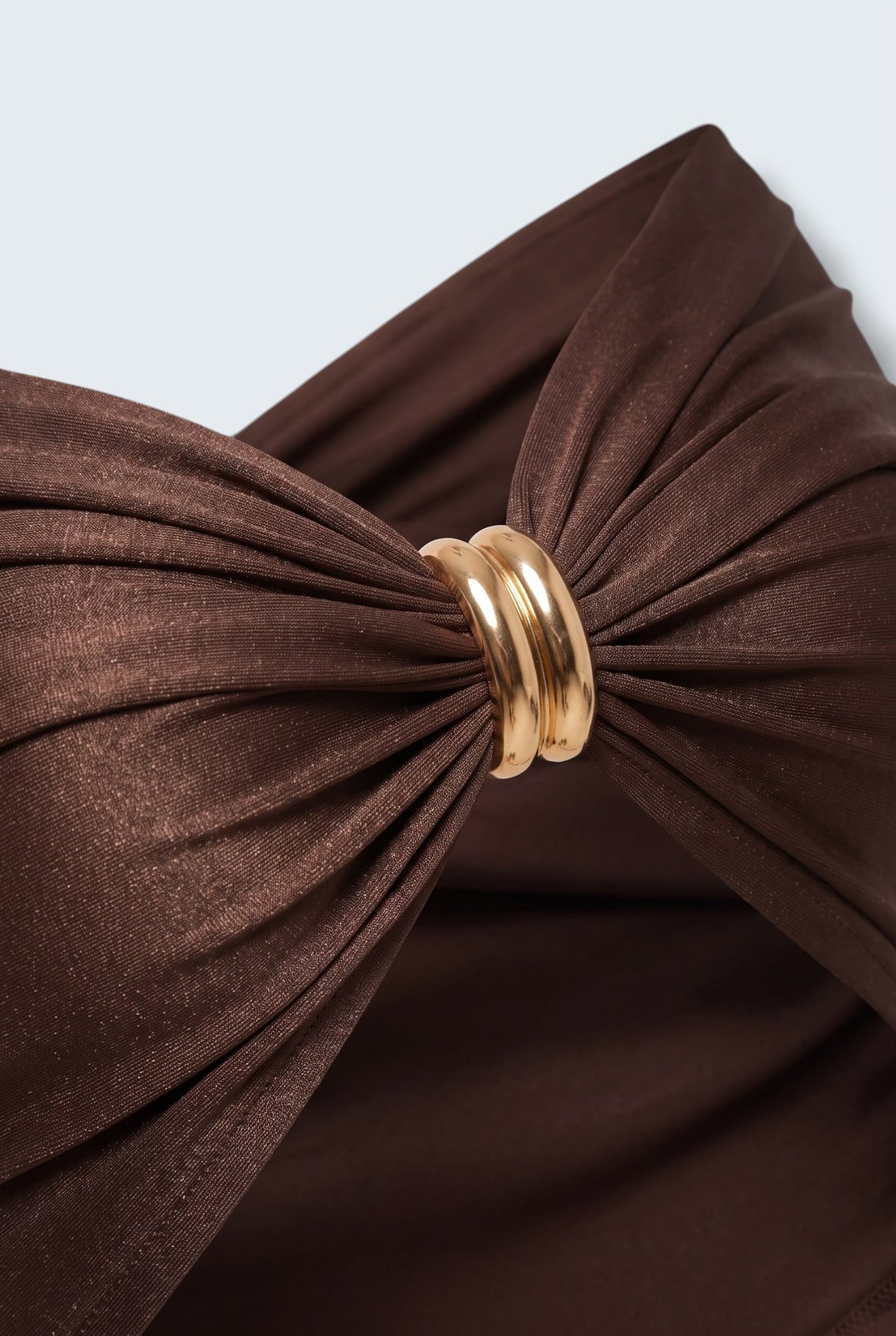 The Saint 54 Bad Girl top in dark chocolate stretch fabric with a central gold ring detail and elegant draping.