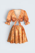 The Saint 54 orange floral two-piece set with a tie-front puff sleeve top and a high-waisted flared mini skirt.