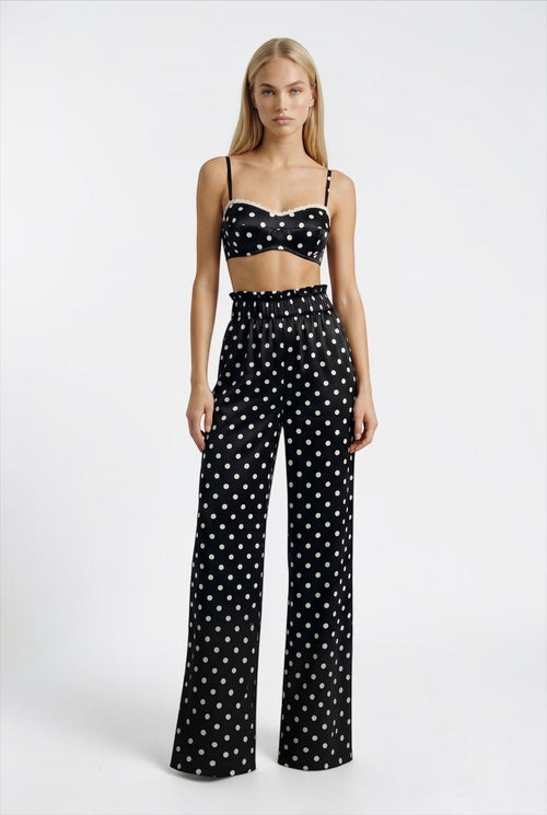 The Saint 54 black and white polka dot crop top with delicate ecru lace trim and adjustable straps on a model.