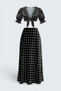 The Saint 54 black and white polka dot two-piece set with a tie-front puff sleeve top and bias-cut midi skirt.