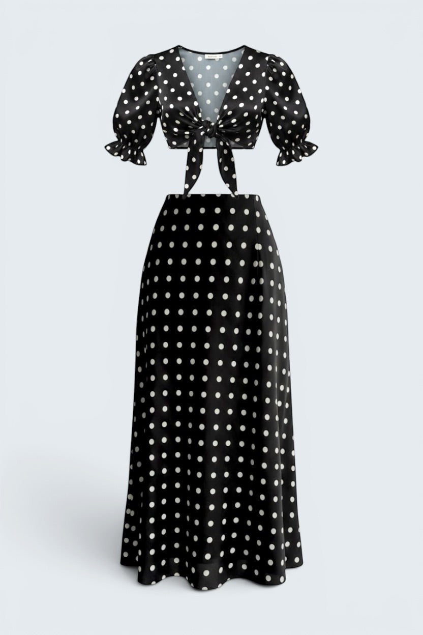 The Saint 54 black and white polka dot two-piece set with a tie-front puff sleeve top and bias-cut midi skirt.