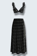 The Saint 54 black and white polka dot two-piece set featuring a ruffled bralette top and a bias-cut midi skirt.