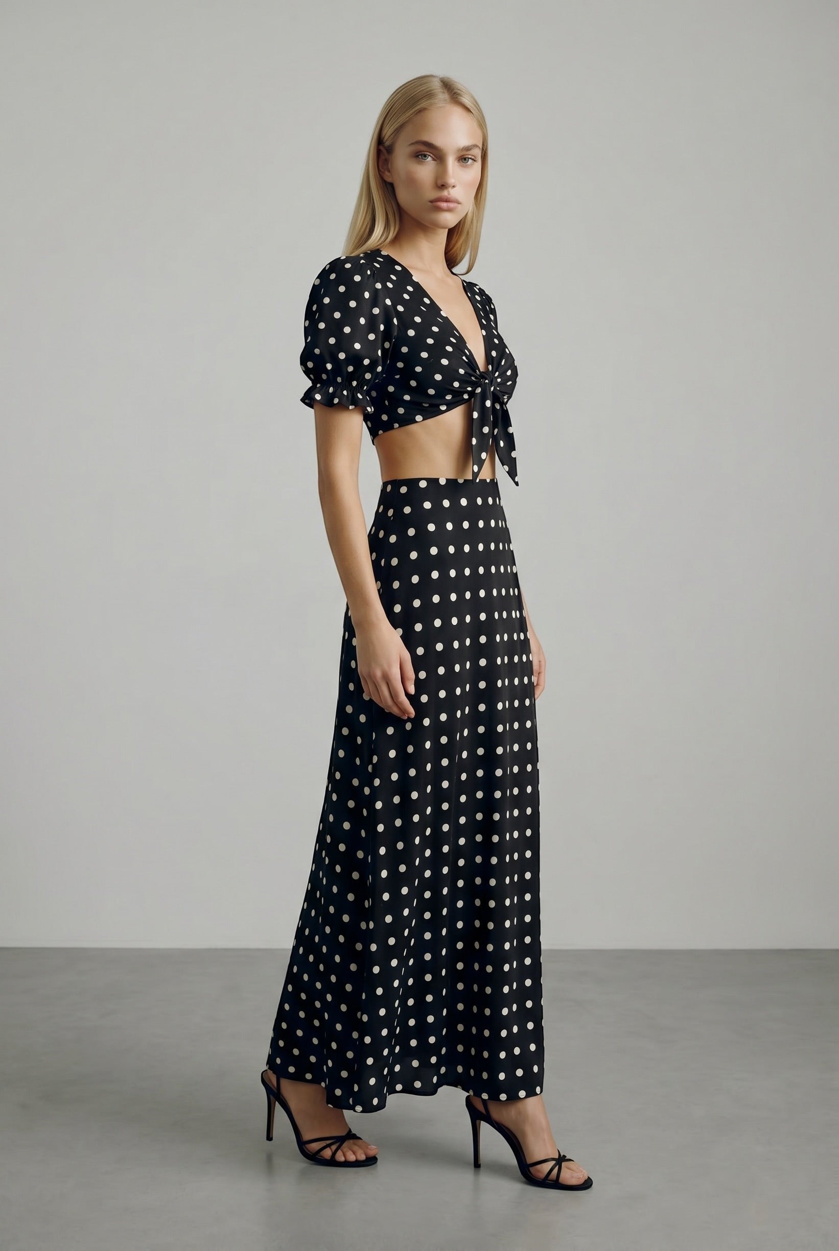 The Saint 54 black and white polka dot two-piece set with a tie-front puff sleeve top and bias-cut midi skirt.