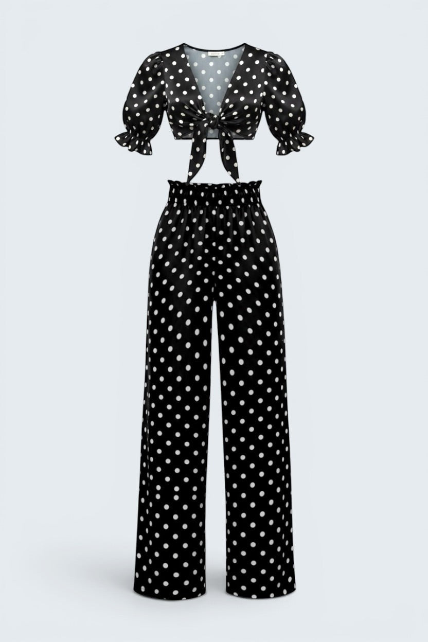 The Saint 54 black and white polka dot two-piece set with a tie-front puff sleeve top and high-waisted wide-leg pants.