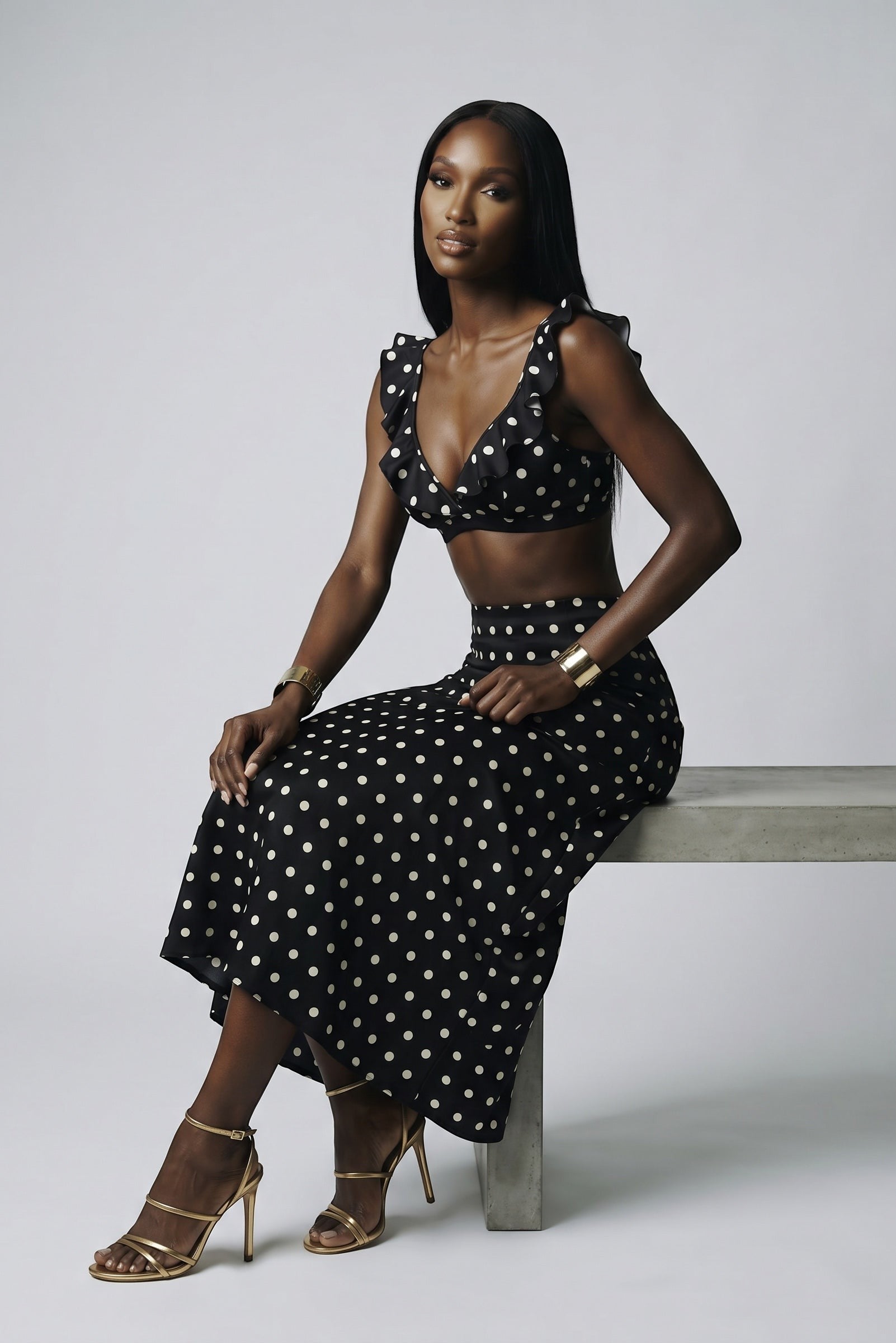 The Saint 54 black and white polka dot two-piece set with a ruffled crop top and bias-cut midi skirt on a model.
