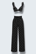 The Saint 54 black and white polka dot two-piece set featuring a ruffled crop top and high-waisted wide-leg trousers.