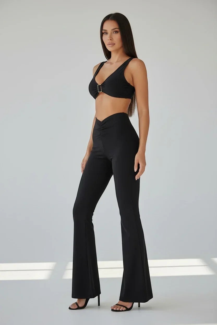 The Saint 54 black lycra V-neck crop top with gold buckle detail and matching flared ruched trousers.
